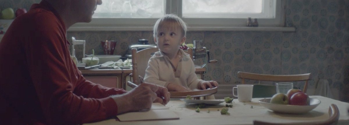 Ein Vater mit Kind in einer Küche der 60er Jahre, am Fenster Eisblumen