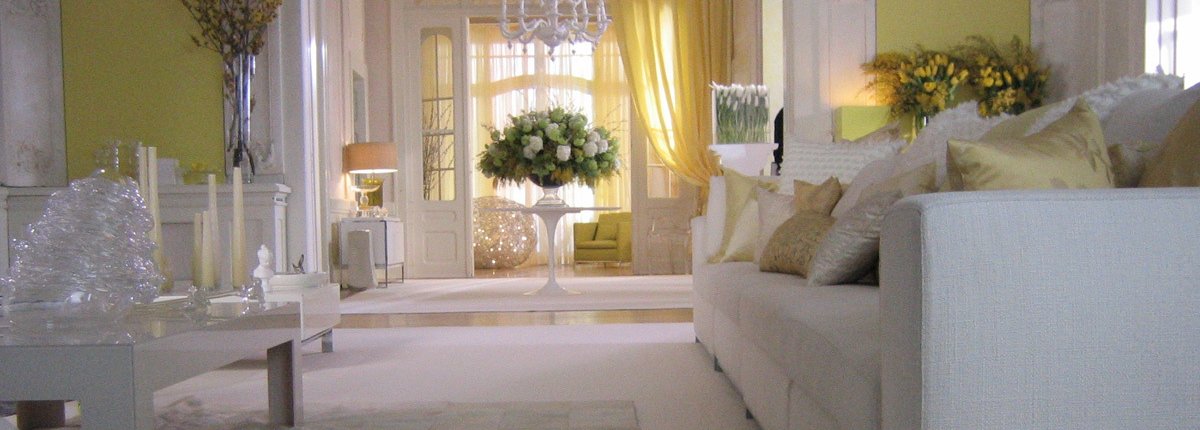 Ein luxuriös ausgestatteter, in weiss und hellgelb gehaltener Salon in einem Altbau mit opulentem Blumenbouquet