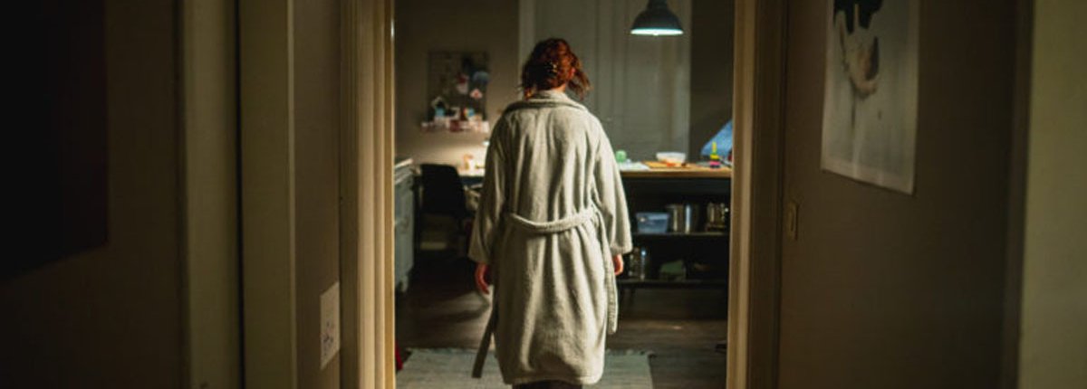 In einer moody Wohnung läuft eine Frau mit roten Haaren in einem Bademantel durch ihre Küche